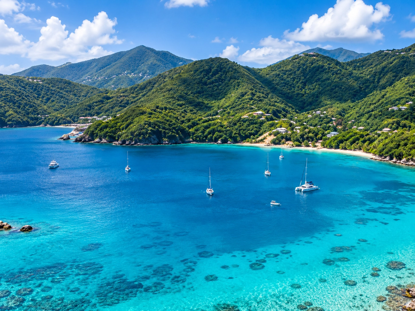 Aerial view of a turquoise bay surrounded by lush green mountains in the U.S. Virgin Islands.
